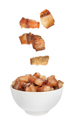 Tasty fried cracklings falling into bowl on white background. Cooked pork lard