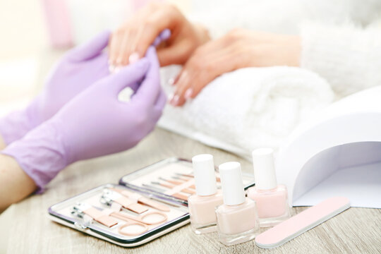 Manicurist in gloves making manicure for client in salon