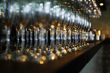 Clean wine glasses prepared by bartender and hung on the bar at a restaurant or cafe.