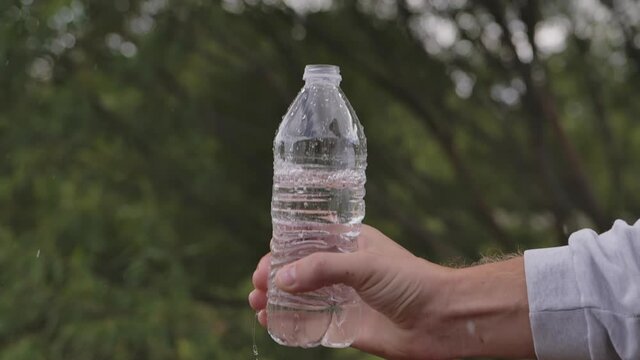 Closeup slow motion water falling down from bottle with drops splashing. High quality FullHD footage