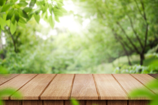 empty wooden table in nature outdoor for free space for product. Natural template with Beauty bokeh and sunlight. Beautiful Spring concept with green nature outdoor