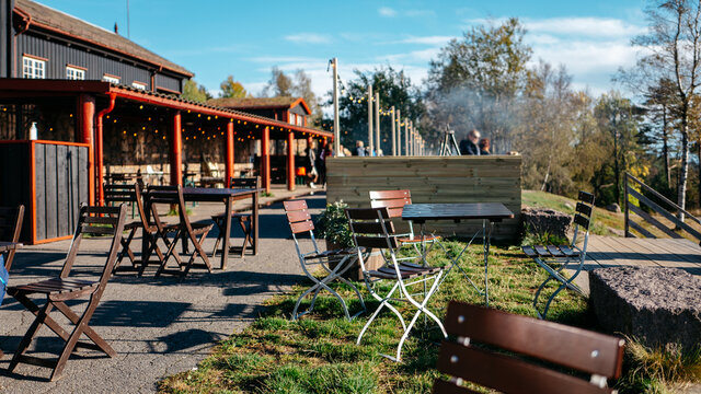 Wooden chairs and tables in outdoor restaurant with people in the background