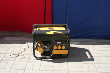 An autonomous portable diesel generator for supplying electricity in yellow stands on the street near the stalls with food