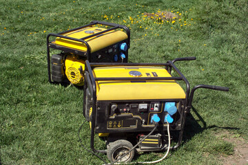 Autonomous portable yellow diesel generator stands on the grass - obrazy, fototapety, plakaty