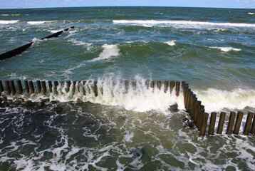 Epic seascape. Storm clouds over the Baltic Sea, a view from the high shore of waves and spray from wooden breakwaters