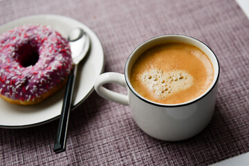 white cup with coffee and doughnut on a purple background. breakfast