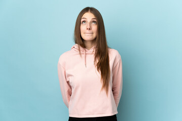 Young caucasian woman isolated on blue background and looking up