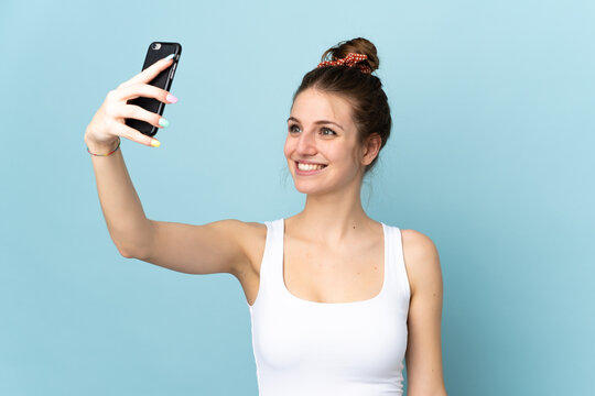 Young caucasian woman isolated on blue background making a selfie