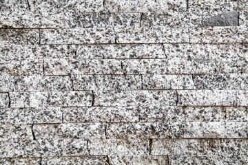 The background of the wall is made of natural granite strips of gray color with black inclusions. Backgrounds texture design.