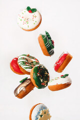 Flying Christmas donuts. Colorful doughnuts with sprinkles falling or flying in motion against white background.  Selective focus