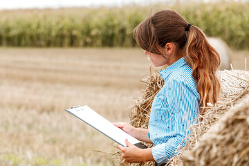 Beautiful girl agronomist with note book and analyzes the corn crop