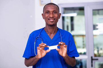 young male doctor holding a small white box of medication smiling.