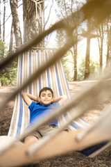 Happy child boy lying in a hammock in garden. Summer holidays concept