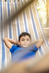 portrait of Happy kid boy lying in a hammock in garden