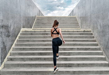 Woman in black sport suit running on the stairs to the heaven