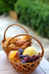 Two baskets full of fresh fruit and vegetable in a garden. Selective focus.