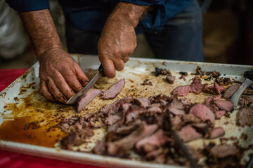 Man cutting piece of meat with knife on table