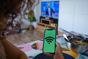 Woman using an app on her mobile phone to control the appliances in her smart home. IoT Internet of Things concept.