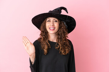 Fototapeta premium Young caucasian woman celebrating halloween isolated on pink background saluting with hand with happy expression