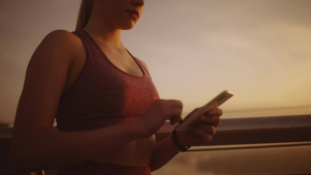 Athletic woman browsing workout tracking app on smartphone, going for a run