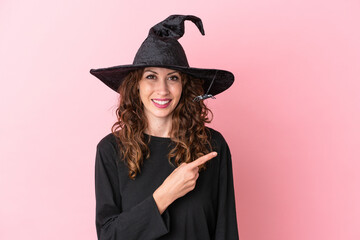 Young caucasian woman celebrating halloween isolated on pink background pointing to the side to present a product