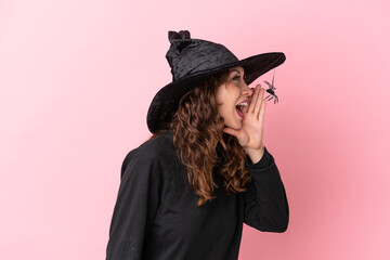 Young caucasian woman celebrating halloween isolated on pink background shouting with mouth wide open to the lateral