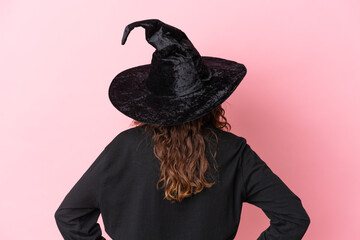 Young caucasian woman celebrating halloween isolated on pink background in back position