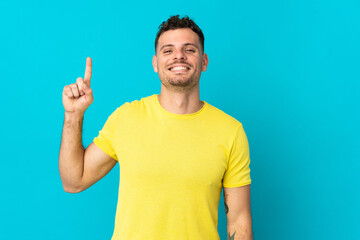 Young caucasian handsome man isolated on blue background pointing up a great idea