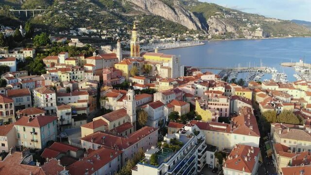 Drone flight over colorful houses of Menton, Cote d'azur, French Riviera. Sunny day, Mediterranean sea, blue sky. Aerial View. 4K 60fps