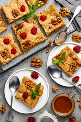 Sweet blondies (blonde)  brownies dessert with walnuts and raspberries on a white plates. Top view