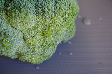 fresh green broccoli lies on a gray board with drops of water . top view . raw green vegetable