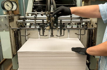 Old large format printing press. Woman's hands are holding paper.