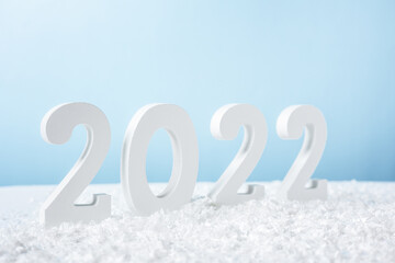 Happy New Year 2022. Decorative white number 2022 with snow isolated on blue background. Greeting christmas card with copy space.