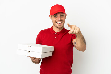 pizza delivery man with work uniform picking up pizza boxes over isolated  white wall surprised and pointing front