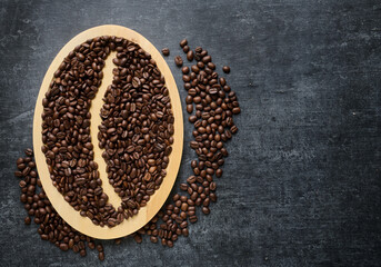 Freshly roasted coffee beans on a wood plate, gray grunge background with space for text