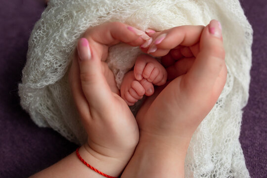 baby feet in the hands of the mother. parents rings on the toes of a newborn