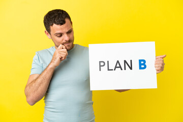 Brazilian man over isolated purple background holding a placard with the message PLAN B and thinking