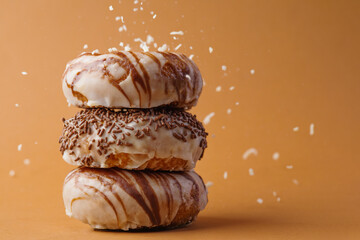 Stack of sugar donuts covered with chocolate icing on a beige background. Confectionery sprinkles...