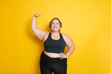 Hispanic overweight fitness model wearing sportswear in strong and fearless pose raising arm. Body Positive And Sport As Lifestyle. Showing muscules