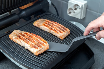 The chef prepares trout on an electric grill. Healthy food. Chef's hand. Homemade food. Photo