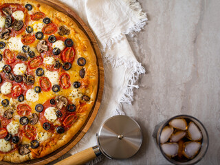 Beautiful composition - Italian pizza on a wooden platter, a knife and a glass of drink with ice....