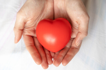 red heart in woman s palms on grey background