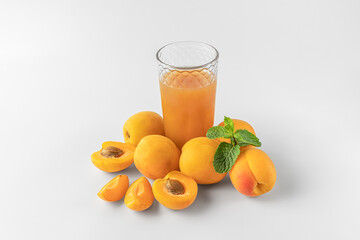 slices of fresh orange apricot with green mint and glass with citrus juice isolated on a white and gray background with natural shadow