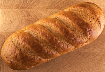 A whole loaf of bread on a wooden board, view from the top