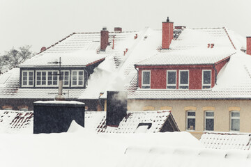 Snow covered rooftops in the city and white sky. Symbol for christmas holidays and winter season