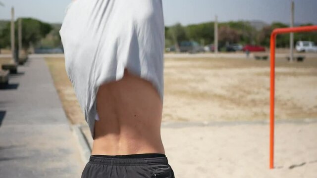 Young man taking off his shirt before starting calisthenics.