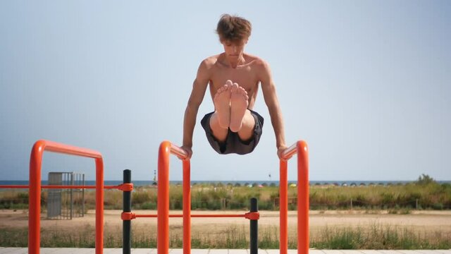 Young blonde man practicing calisthenics on parallel bars.