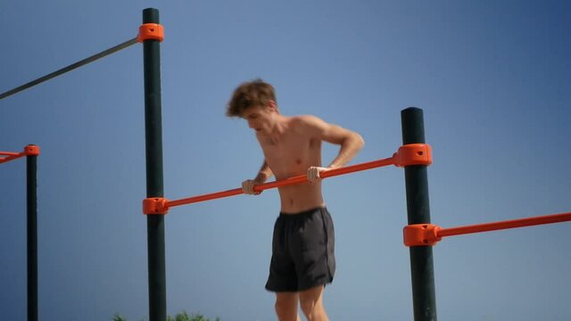 Young man doing muscle up on a bar practicing calisthenics exercices.