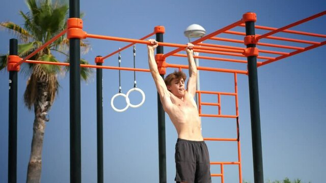 Young man doing muscle up on a bar practicing calisthenics exercices.