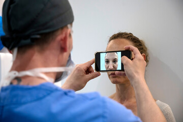 Aesthetic surgeon taking photograph of patient before operation
